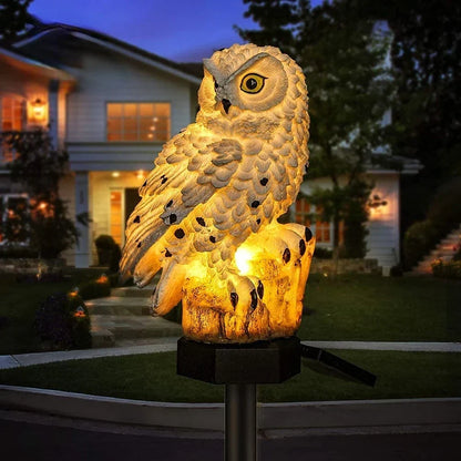 Single white owl light with black spots glowing on its tree-stump perch, lit up in front of a house at night. 2