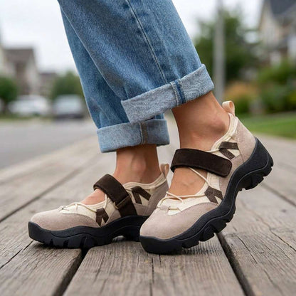 Taupe and cream shoes with brown straps worn with rolled-up jeans, standing on a wooden boardwalk in a residential street. 6