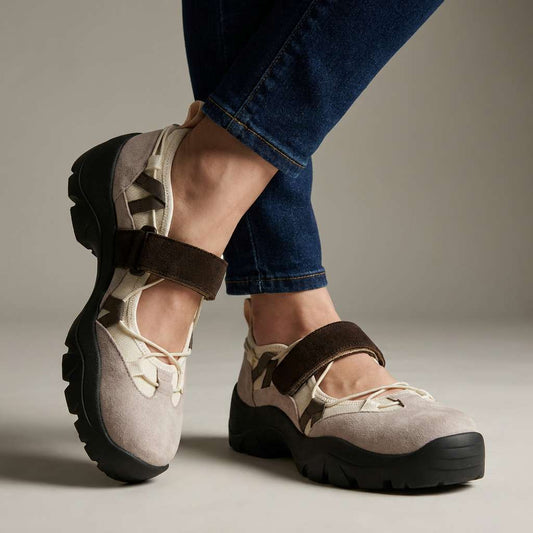 Worn with dark skinny jeans in a studio, taupe suede shoes with a brown hook-and-loop strap, cream elastic lacing and chunky black soles. 1