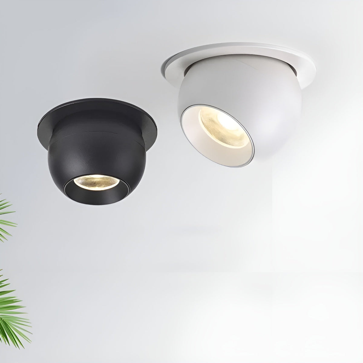 Black and white recessed spotlights lit on a pale ceiling, with a green palm leaf at the edge 7
