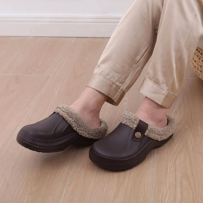 Person wearing dark brown fur-lined clogs with grey leggings, seated on a wooden floor 10