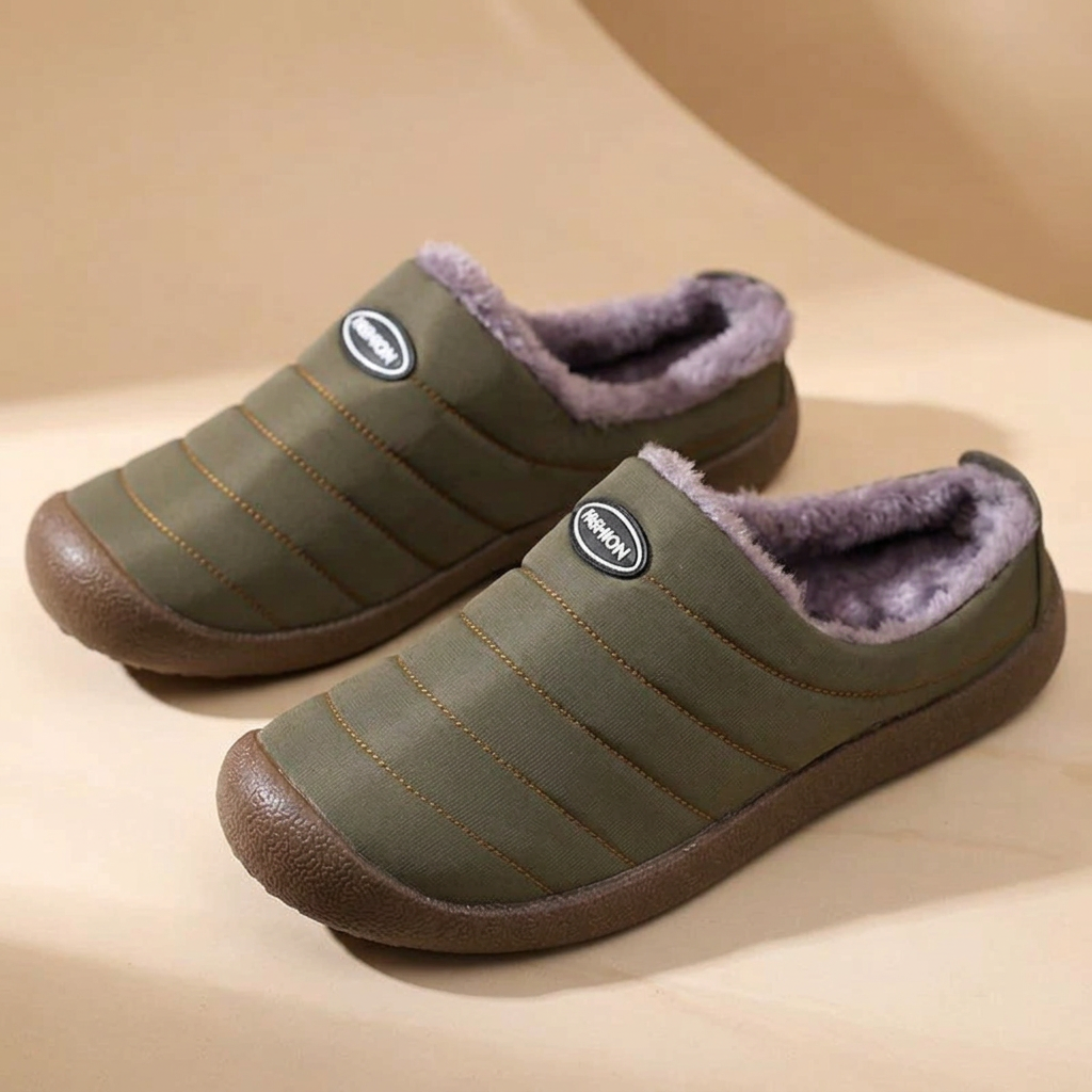 Pair of olive green slippers with purple-grey fleece lining on a beige curved backdrop 17