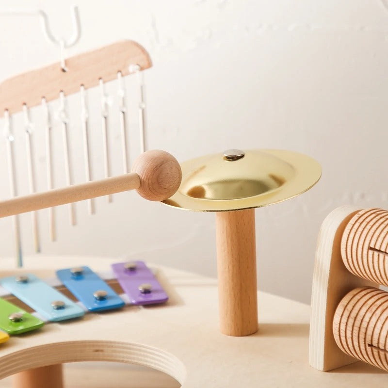 Close-up of the brass cymbal on its wooden post, with chimes, xylophone bars and guiro behind 8