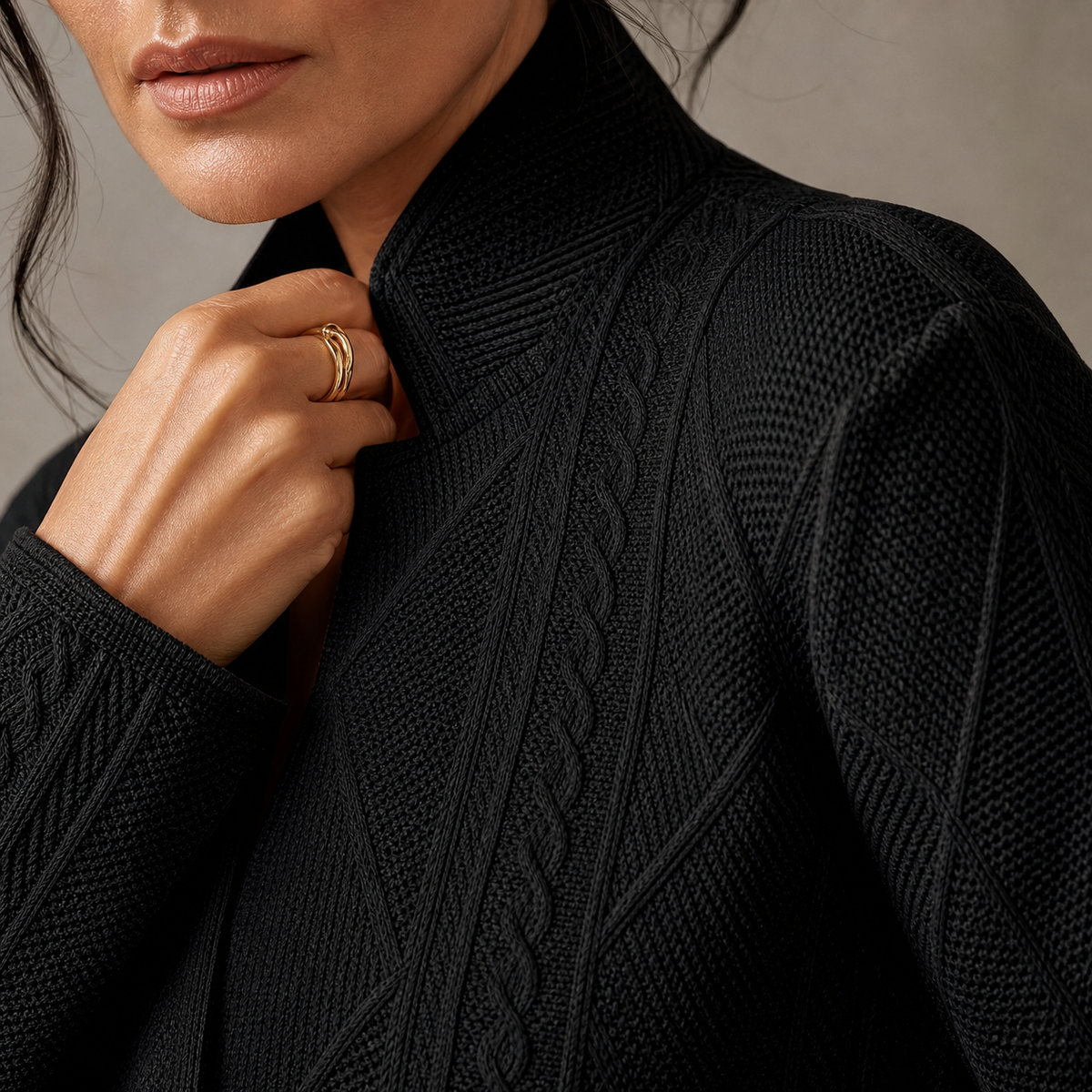 Close-up of the black blazer's stand collar and knit-like cable and diamond texture, with a hand holding the lapel edge. 12