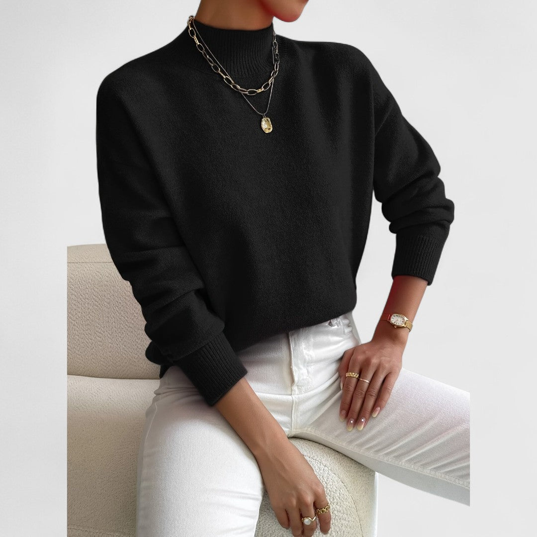 Model wearing the jumper in black with white jeans, showing the contrast with gold necklaces and a gold watch. 8