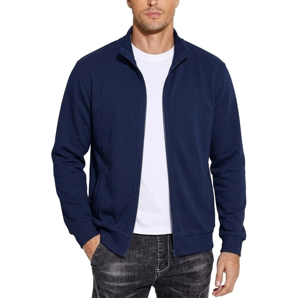 Man wearing the navy blue zip-up jacket open over a white t-shirt, one hand in the pocket, front view. 3