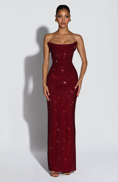 Model facing forward in the floor-length strapless burgundy rhinestone dress, with draped corset bodice and gold earrings. 1