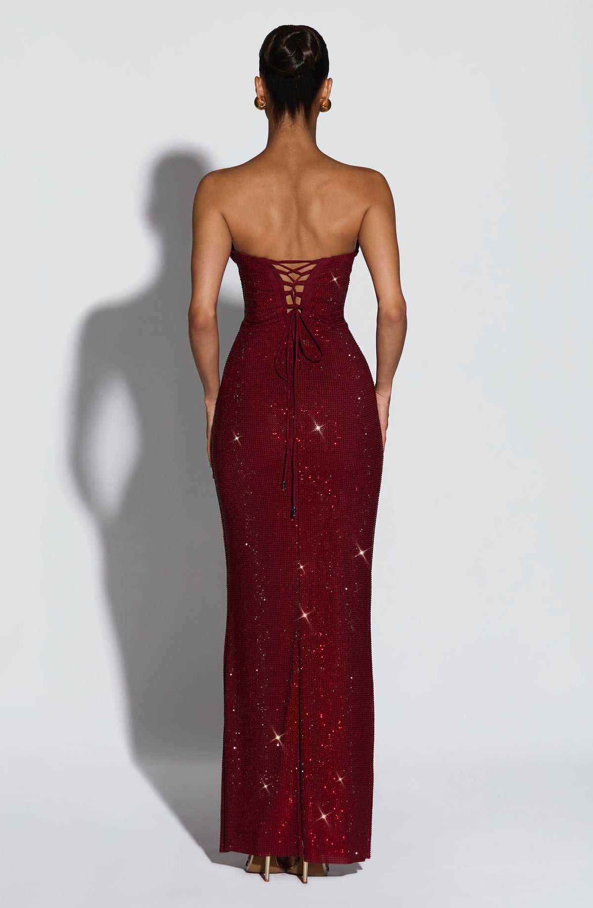 Back view of the burgundy sparkling maxi dress showing the criss-cross lace-up corset back with trailing ties. 2