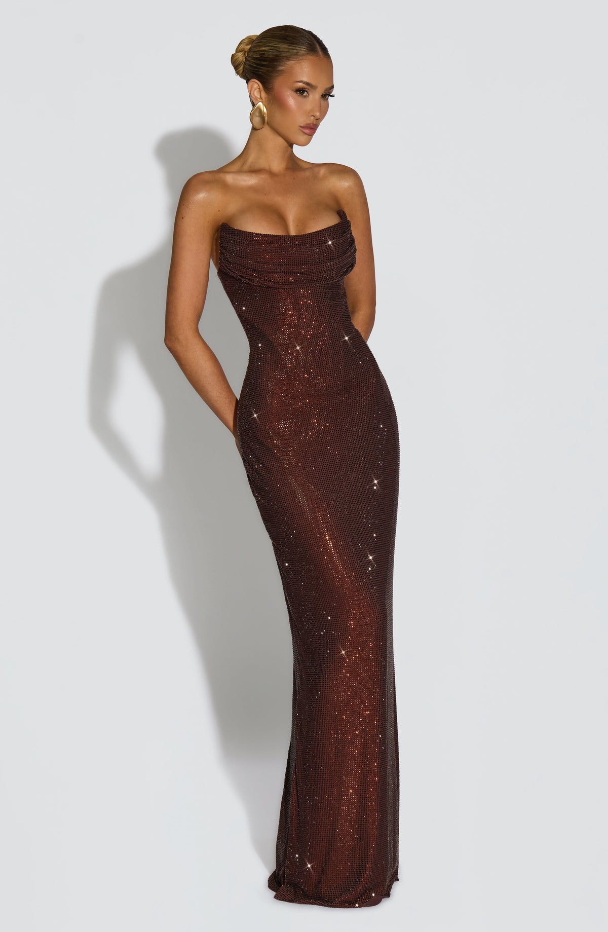 Angled front view of the brown strapless dress with the model's arms behind her, showing the fitted corset shape. 12