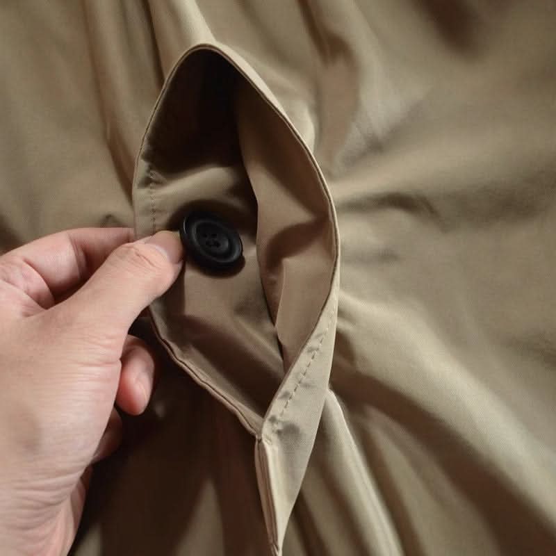 Close-up of a hand holding open a beige coat pocket, with a black four-hole button inside. 8