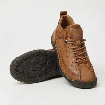 Tan brown leather-look trainers with contrast stitching, one shoe standing and one tilted to reveal the dark brown studded sole. 4