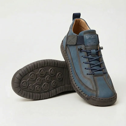 Blue-grey lace-up trainers with navy laces and elastic strap, paired with a view of the dark studded outsole. 6
