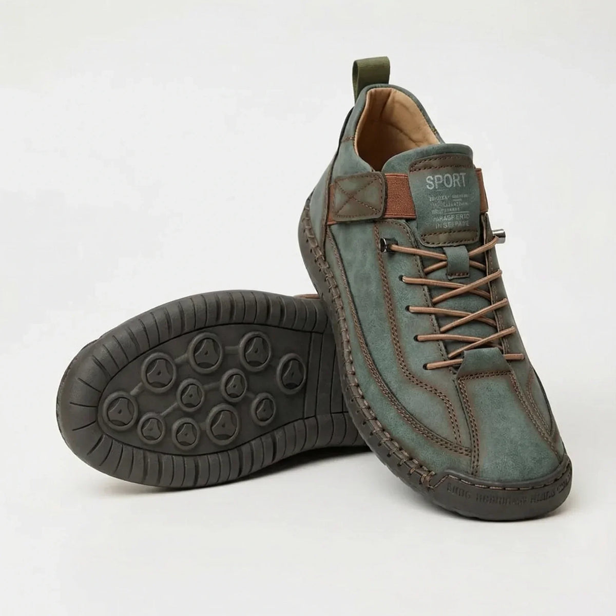 Sage green trainers with brown elastic laces and strap, one shoe upright and one showing the dark rubber sole underneath. 5