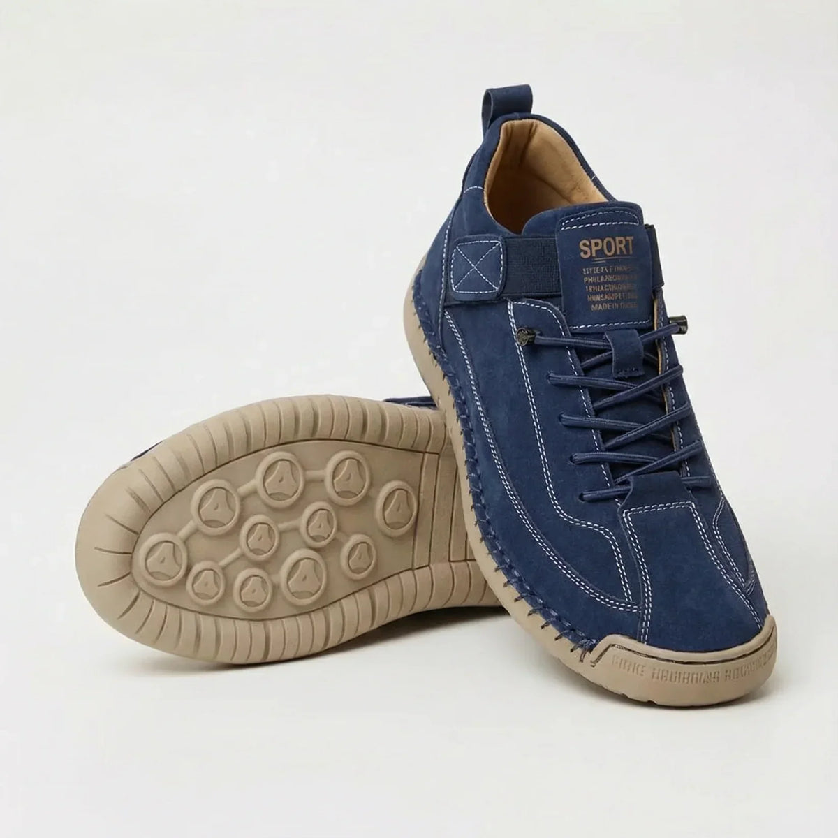 Navy blue suede-style trainers with white contrast stitching and a beige sole, one shoe upright and one showing the tread. 7