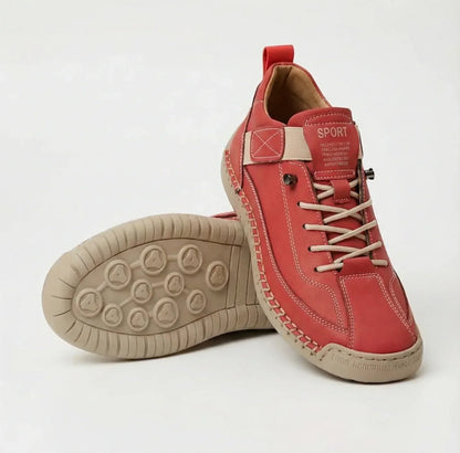 Red lace-up trainers with cream laces, elastic strap and stitching, one shoe upright beside one showing the beige tread. 9