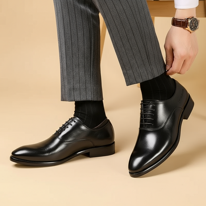 Black leather lace-up shoes on a model in grey pinstripe trousers, adjusting the trouser hem 3