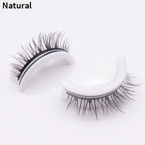 Pair of natural-style lashes on curved white holders, one upright and one on its side, shown against a plain pale background. 11