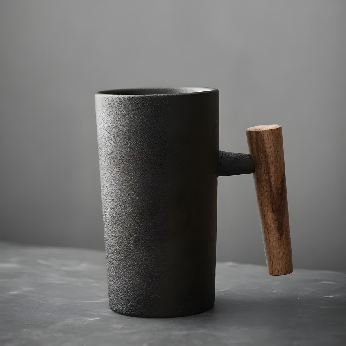Matte black textured stoneware mug with a dark walnut-toned wooden handle, shown side-on against a grey backdrop 2
