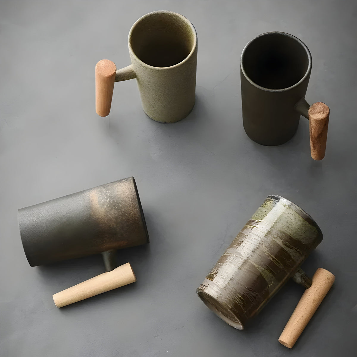 Overhead flat lay of four stoneware mugs, two upright and two lying on their sides, wooden handles pointing outwards 8