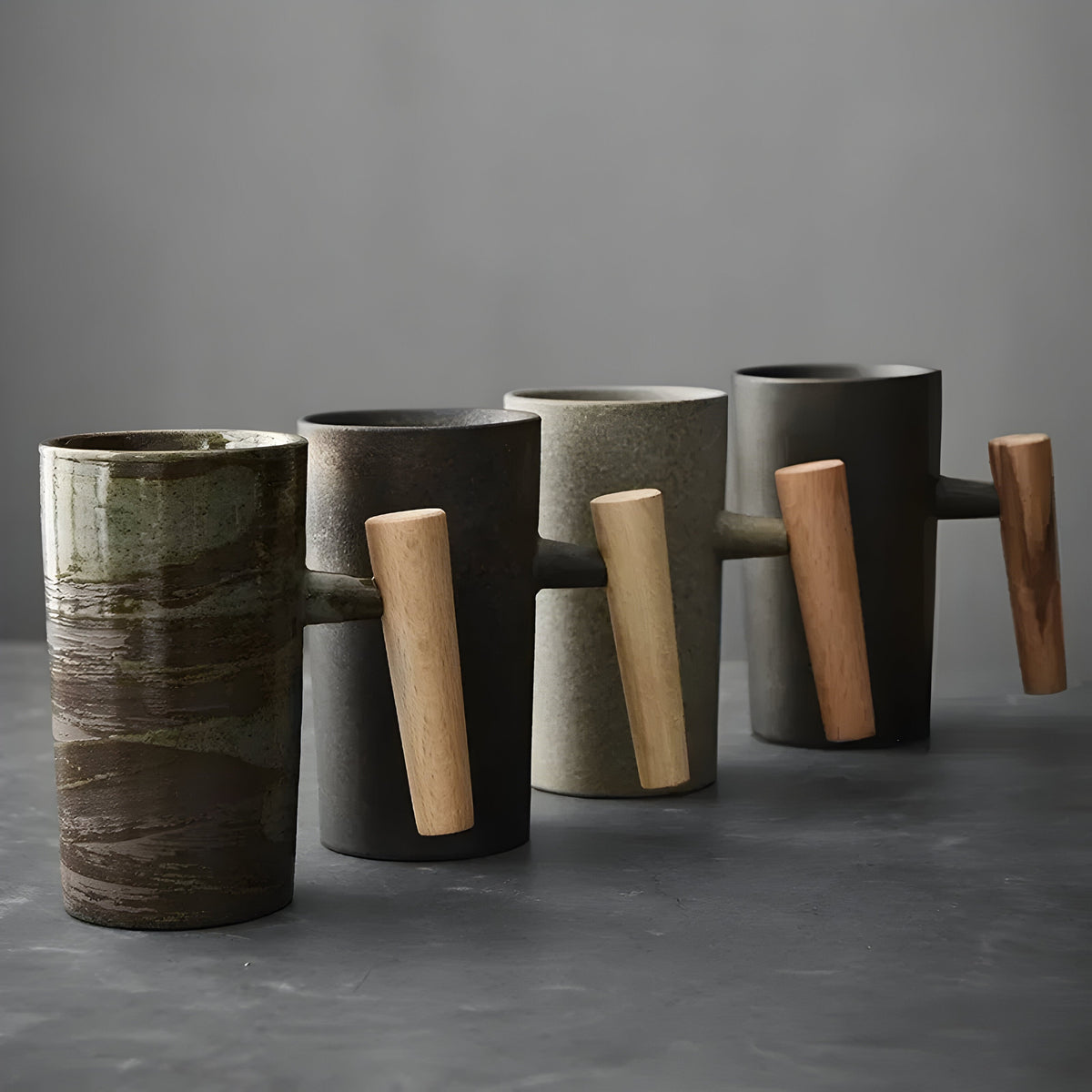 Row of four tall stoneware mugs in different glazes, each with a wooden handle, seen from the handle side 5