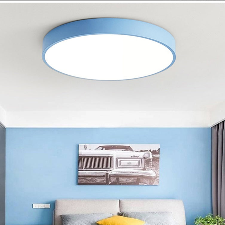 Plain blue round ceiling light without wood trim, lit above a bedroom with blue walls and a framed black-and-white car print. 4