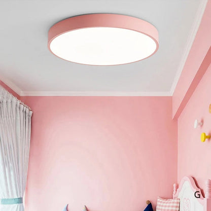 Plain pink round ceiling light without wood trim, switched on in a pink child's bedroom with curtains and a decorative bed. 5