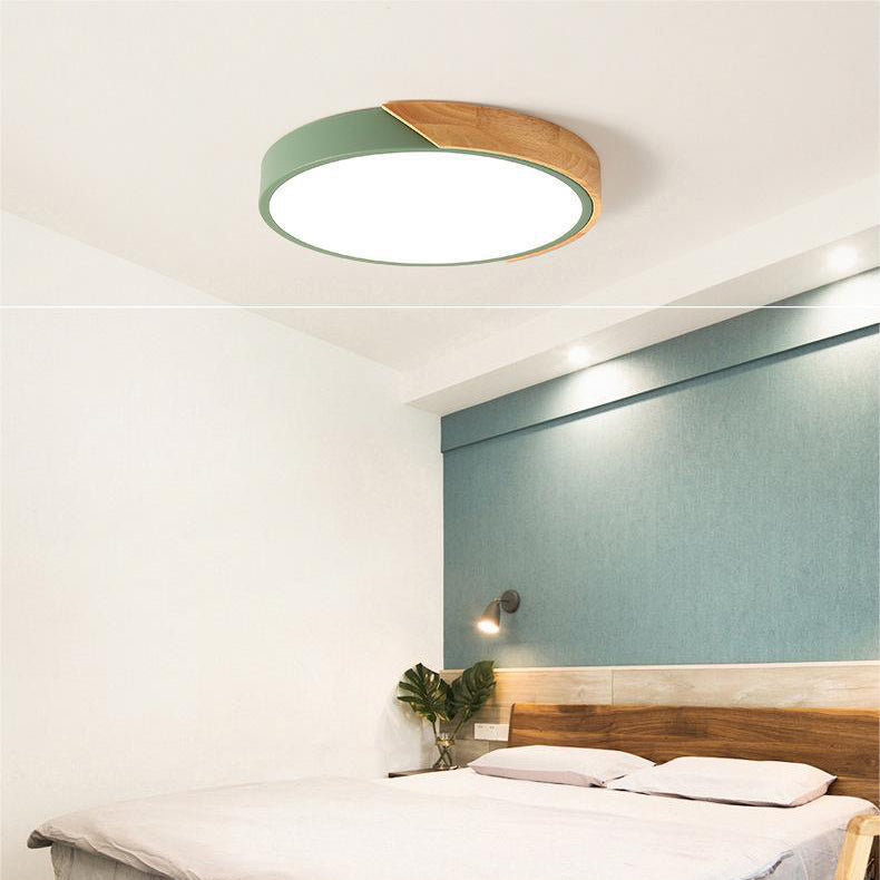 Green round ceiling light with a wooden segment, glowing above a bedroom with a wooden headboard, white bedding and a teal wall. 6