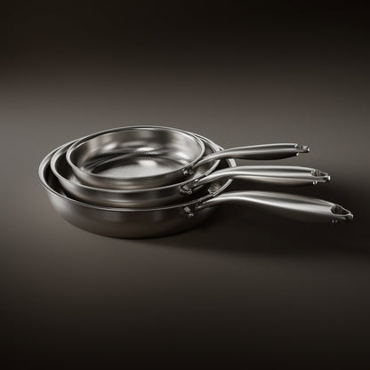 Three hammered metal frying pans nested together by size on a dark background, handles fanned out 1