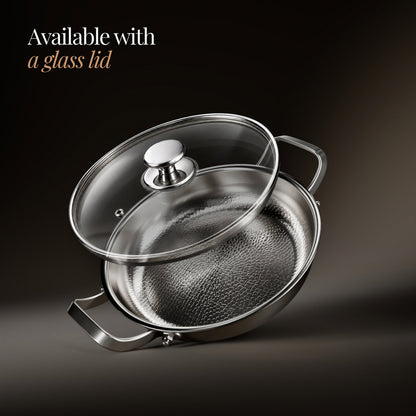 Pan tilted at an angle with a clear glass lid lifted above it, showing the metal knob and the hammered interior. 3