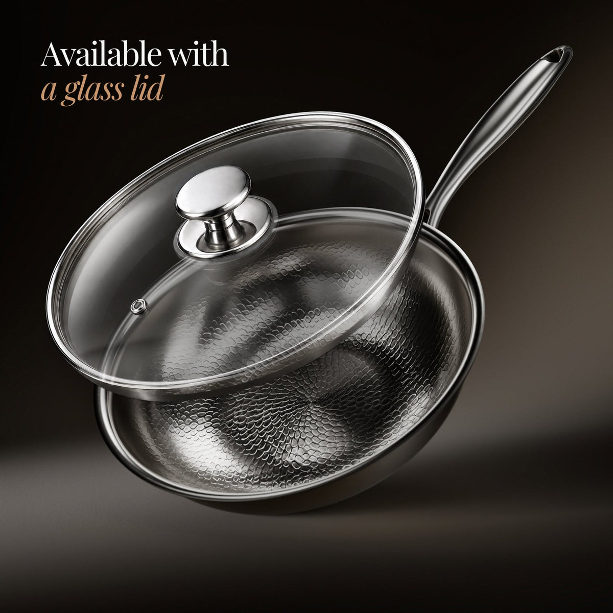 Wok shown with a clear glass lid lifted above it, with a steel knob and steam vent, on a dark backdrop. 3
