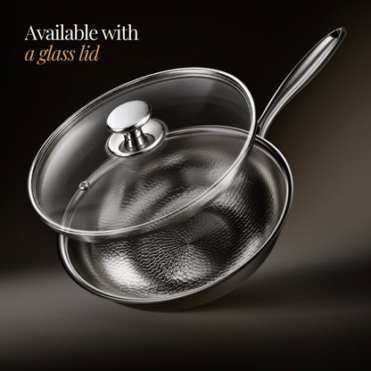 Wok shown with a clear glass lid lifted above it, with a steel knob and steam vent, on a dark backdrop. 3