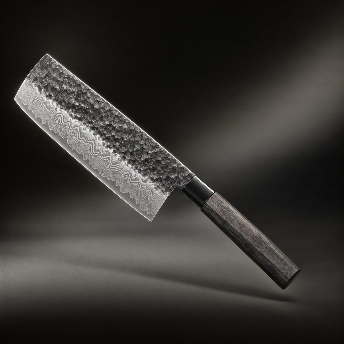 Rectangular-bladed knife angled diagonally against a dark studio backdrop, showing its hammered upper blade, rippled layered-steel edge and dark octagonal woode 1