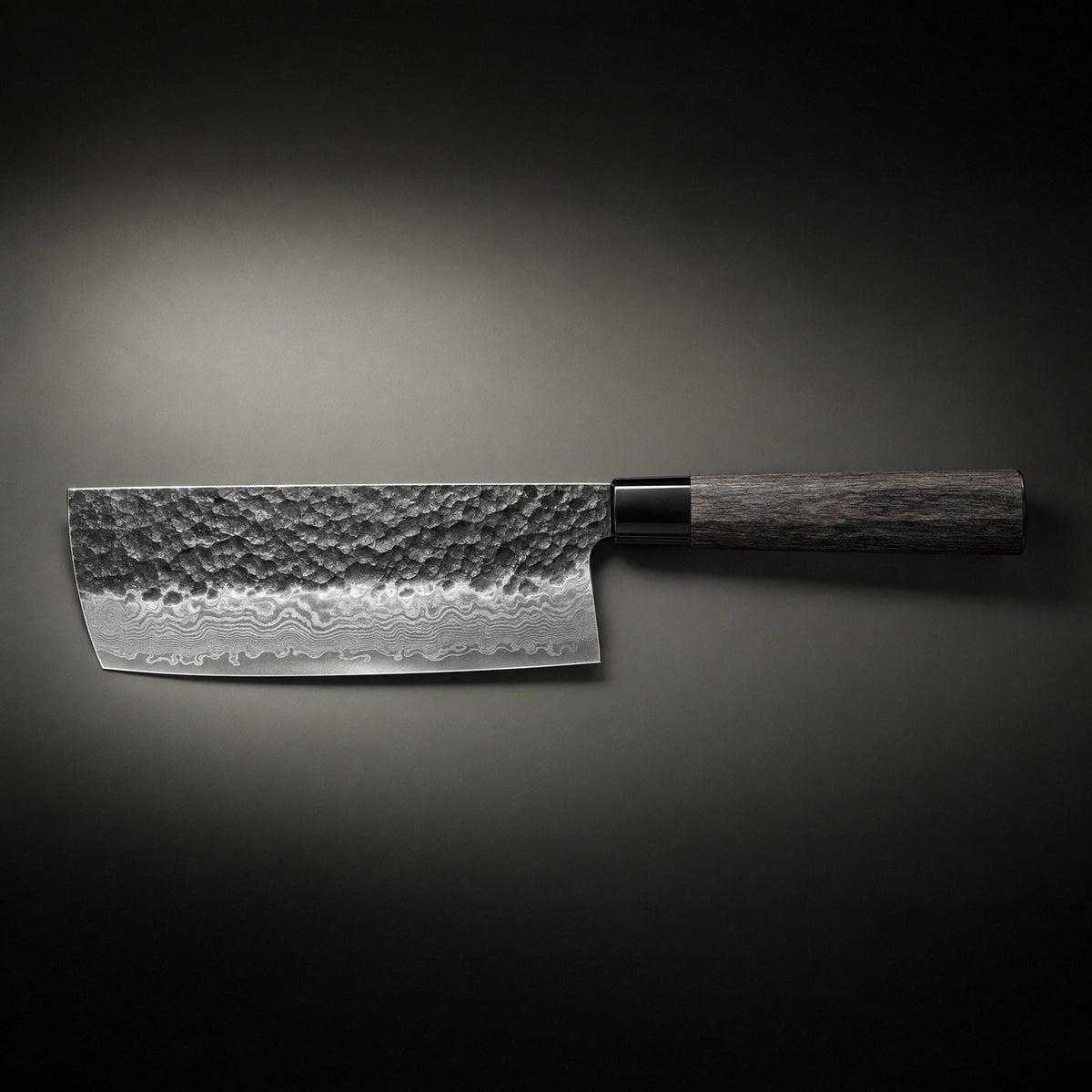 Side view of the knife laid horizontally on a dark background, showing the full hammered blade, rippled steel pattern near the edge and wooden handle. 2