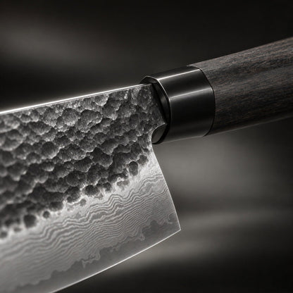 Close-up of the blade where it meets the handle, showing the textured hammered surface, wavy layered-steel pattern, black metal collar and dark wood. 3