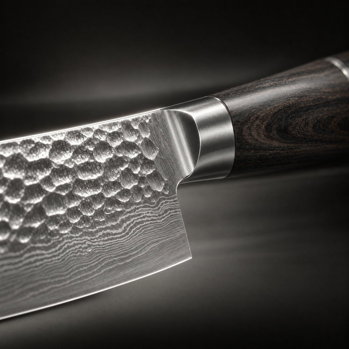 Close-up of the hammered blade near the bolster, with rippled layered steel and wood grain handle 3