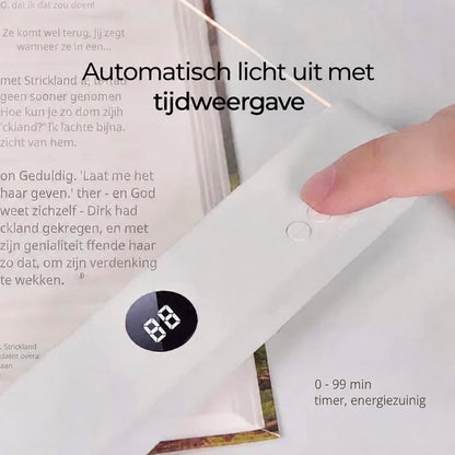 Finger pressing a button on the lamp's base beside a small display, resting on an open book 9
