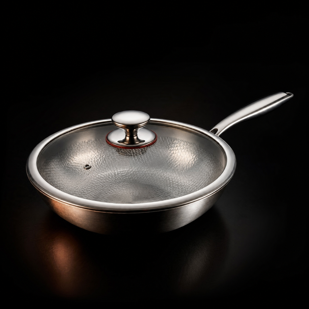 Wok with a clear glass lid and polished metal knob, steam vent visible, shown on a dark background. 3