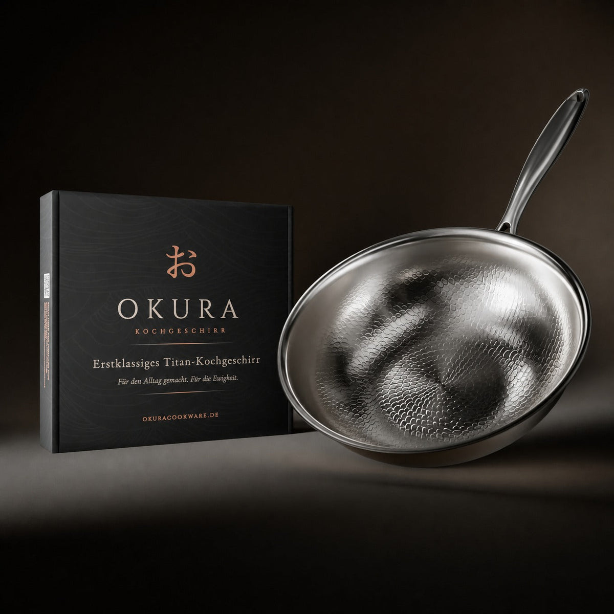Wok pan tilted beside its black gift box with copper lettering, against a dark background. 8