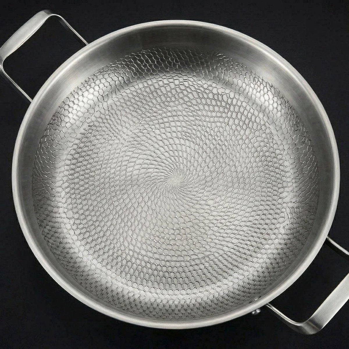 Close top-down view of the pan's interior, filling the frame with the swirling hammered honeycomb texture of the cooking surface. 2