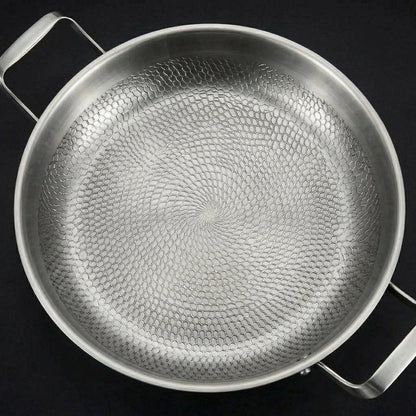 Close top-down view of the pan's interior, filling the frame with the swirling hammered honeycomb texture of the cooking surface. 2