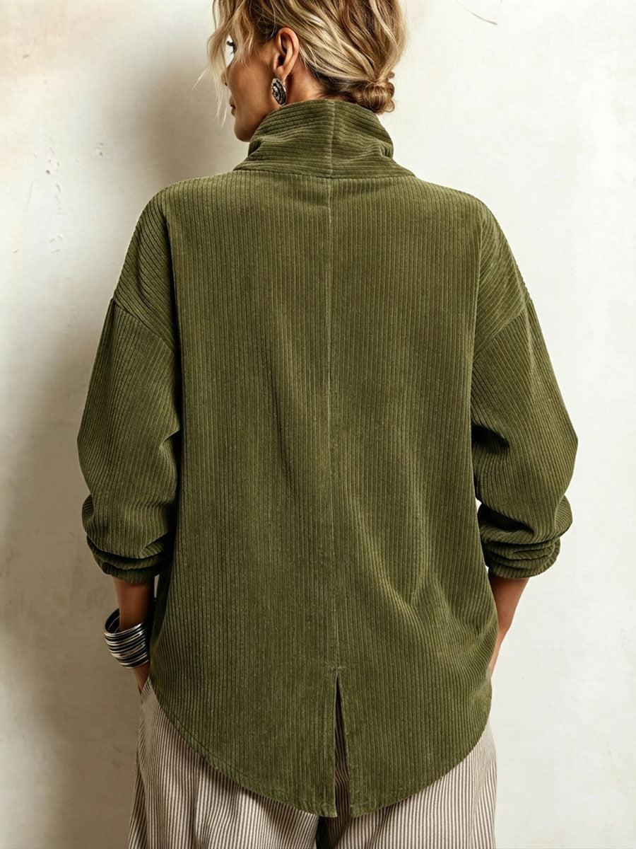 Back view of the olive green corduroy sweater on a model, showing the high collar, centre seam and slit in the curved hem. 2
