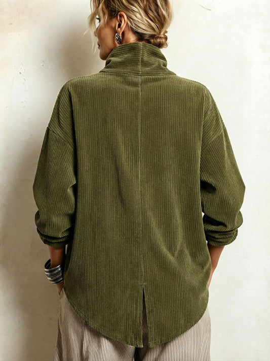 Back view of the olive green corduroy sweater on a model, showing the high collar, centre seam and slit in the curved hem. 2