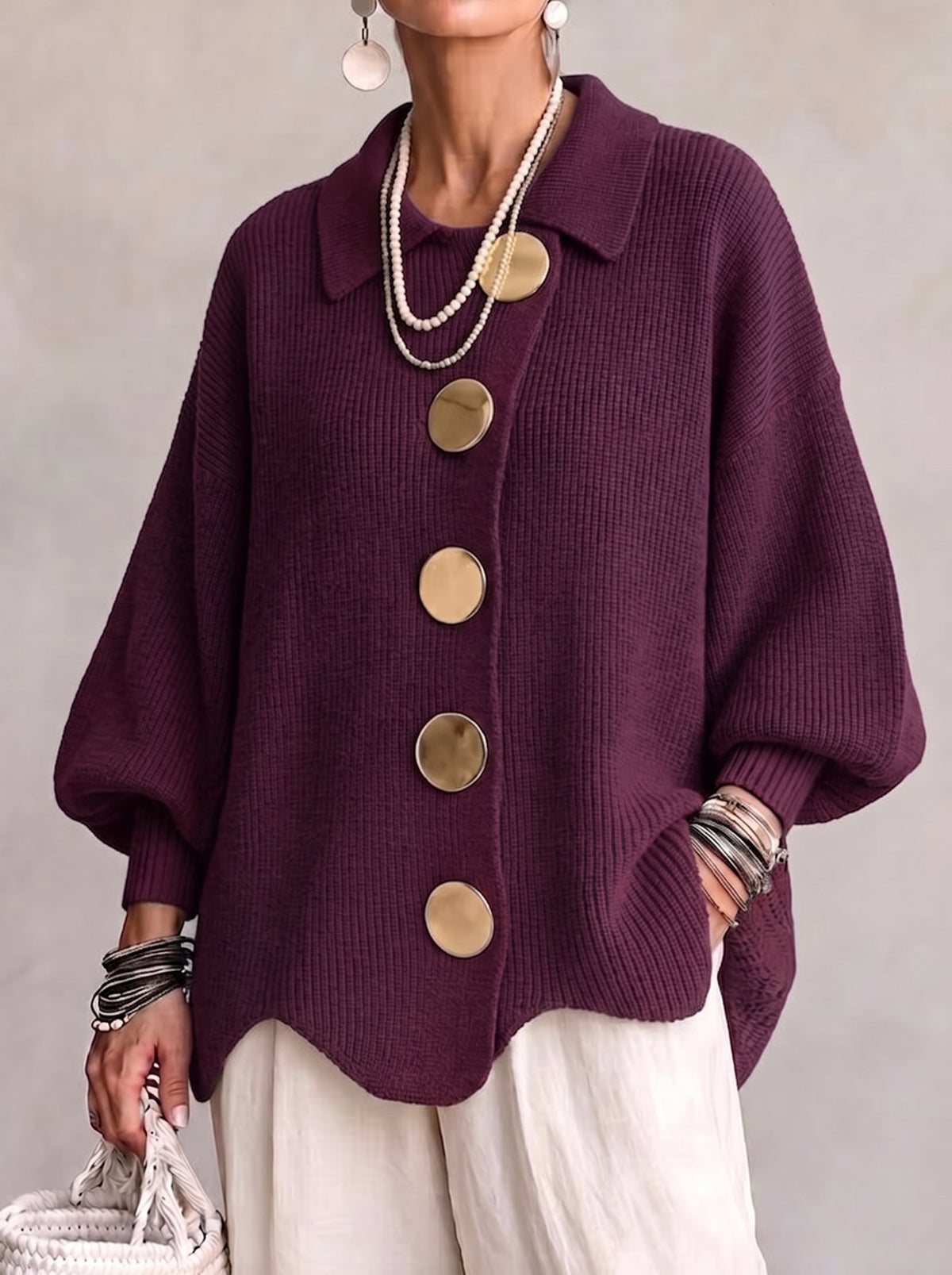 Deep plum ribbed cardigan on a model, showing big gold buttons, pointed collar, balloon sleeves and scalloped hem. 2