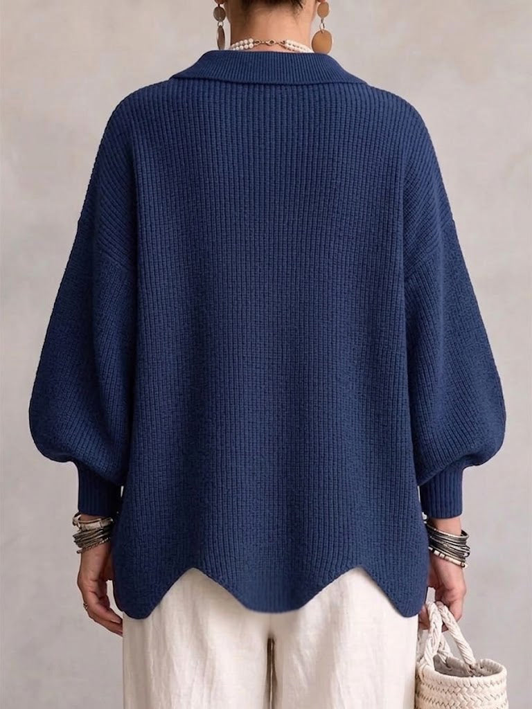 Back view of the navy cardigan on a model, showing ribbed knit, cuffed balloon sleeves and scalloped hem. 16