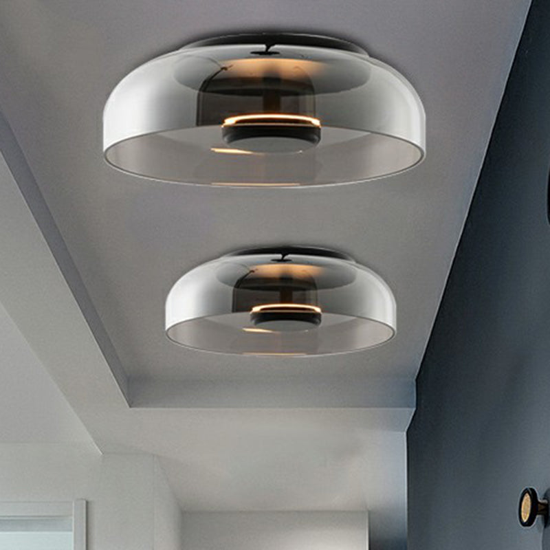 Two smoked grey glass flush lights in different sizes on a hallway ceiling, glowing softly 1