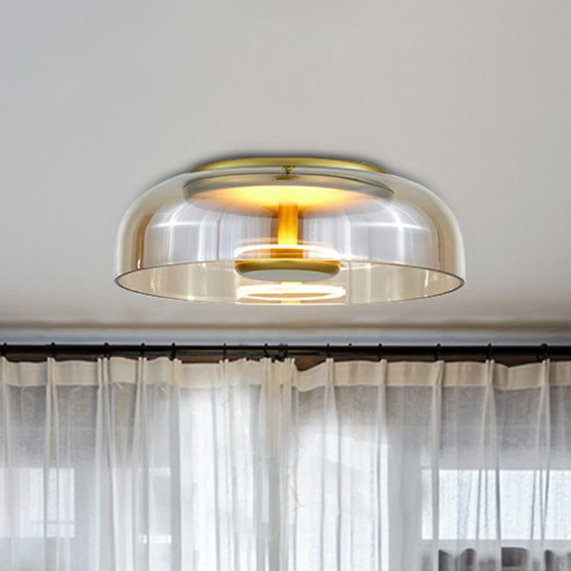 Amber-tinted glass flush light with brass-toned fittings on a ceiling in front of sheer curtains 2