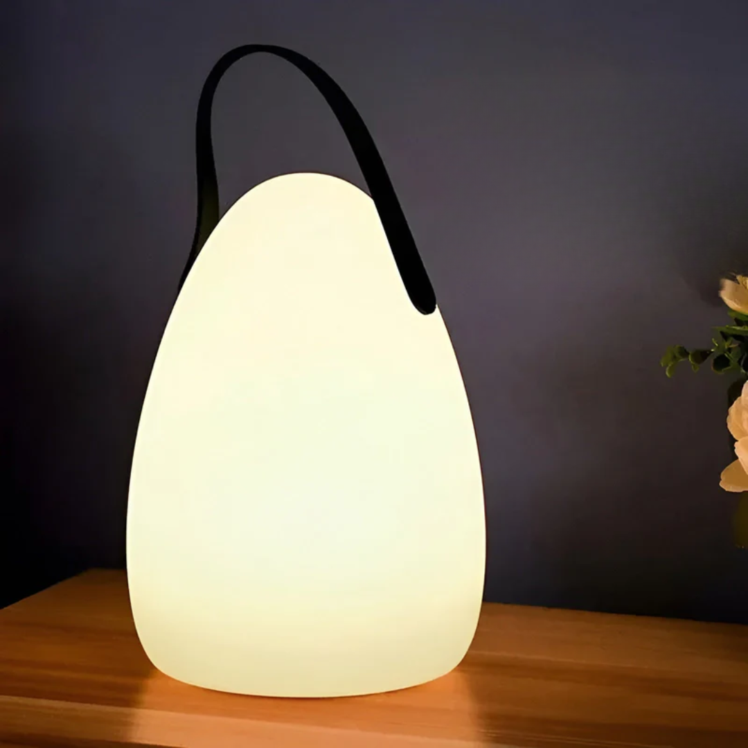Teardrop lamp with black strap glowing on a wooden shelf against a dark wall 13