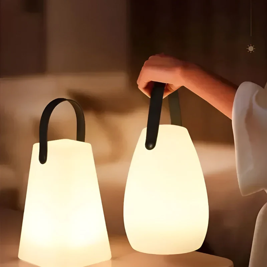 Tapered lamp standing beside a teardrop lamp held by a hand, both glowing warmly 4