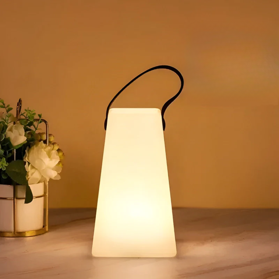 Tapered lamp glowing warm white on a table next to a flower pot with white blooms 11