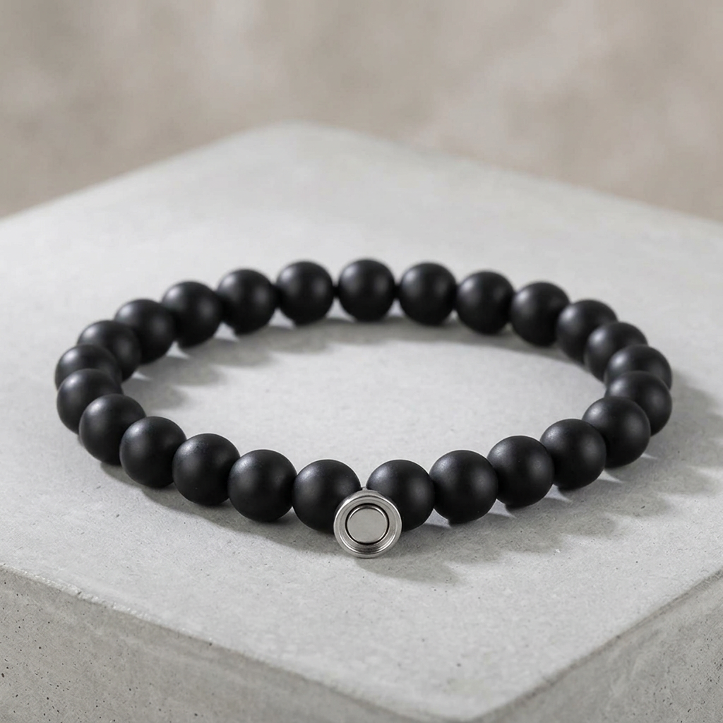 Matte black bead bracelet with silver round magnetic clasp resting on a pale concrete block 2